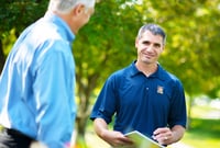 A professional advisor meets with a client outdoors, reviewing documents in a relaxed setting.
