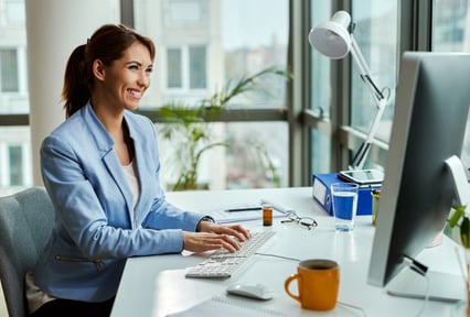 A woman sitting looking at a computer smiling