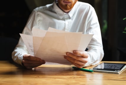 A man in a white shirt reviewing documents at a table