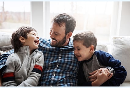 A guy smiling with his arms around his kids