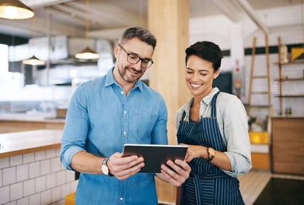 A man and women looking at a tablet smiling