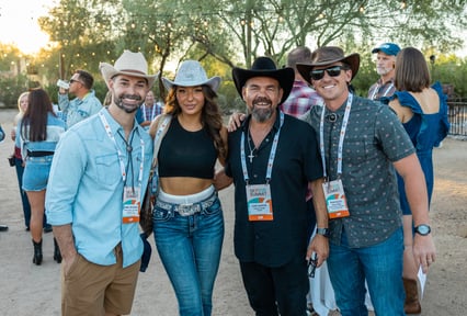 A group of people from SKIP Summit 2025 in cowboy hats smiling at the camera