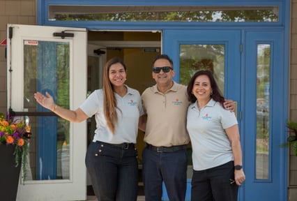 Two women and a man smiling for a photo in front of a store front