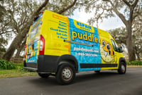 Bright yellow Puddle Pool Services repair van parked on a residential street.