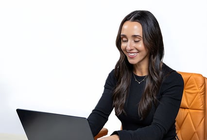 A girl working on a laptop computer smiling