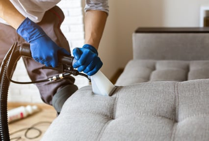 Professional cleaner using an extraction tool to deep clean a fabric sofa.