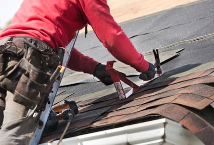A man installing shingles on a roof