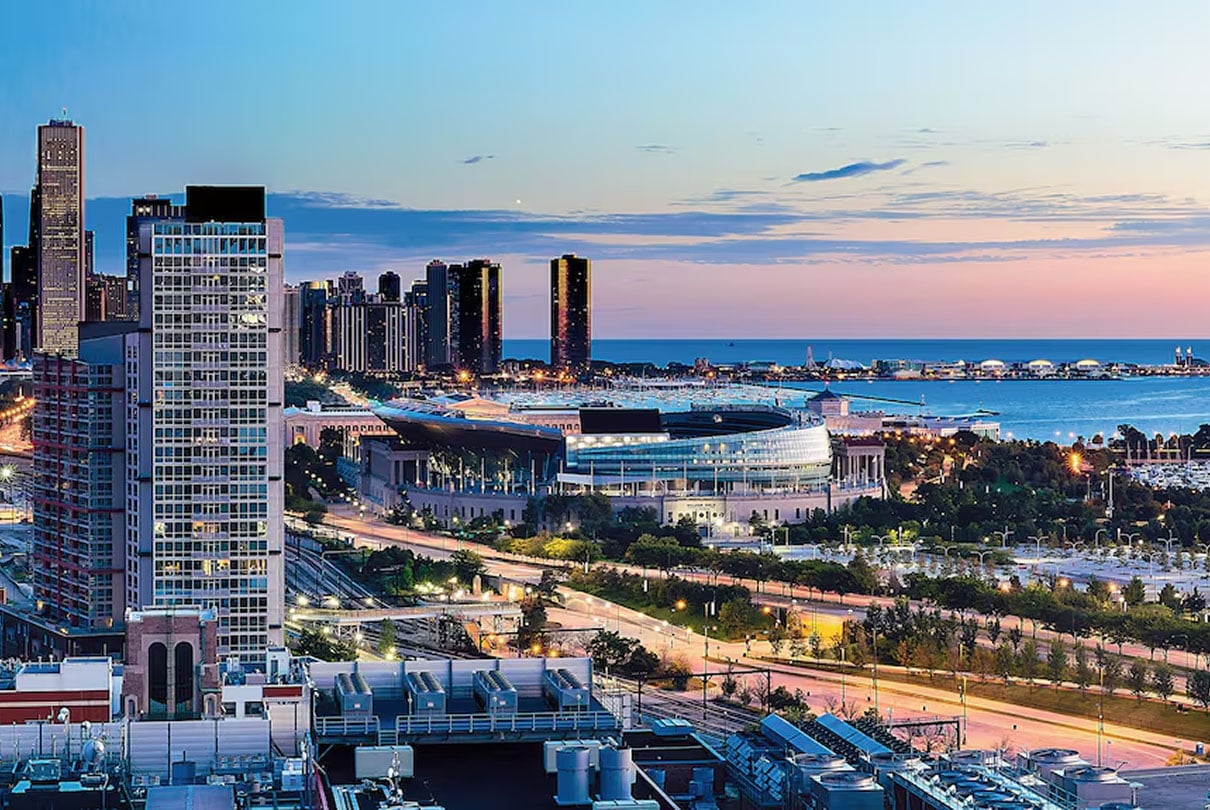 Twilight view of Chicago’s lakefront with McCormick Place and surrounding high-rises, illuminated streets in the foreground, and Lake Michigan stretching into the distance.