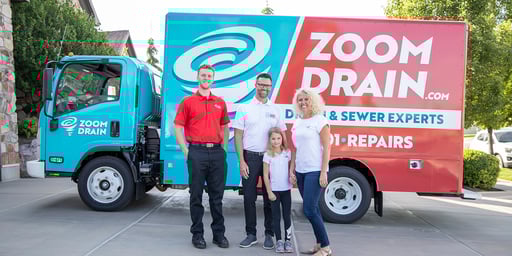 family and employee standing in front of a Zoom Drain truck