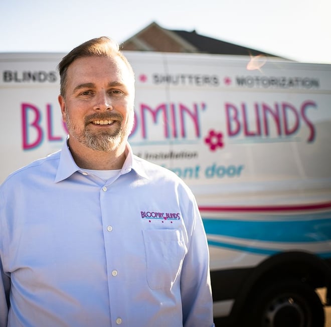 Bloomin' Blinds founder stands in front of branded van.