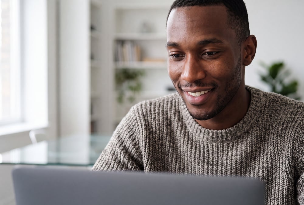 A man looking at his laptop smiling