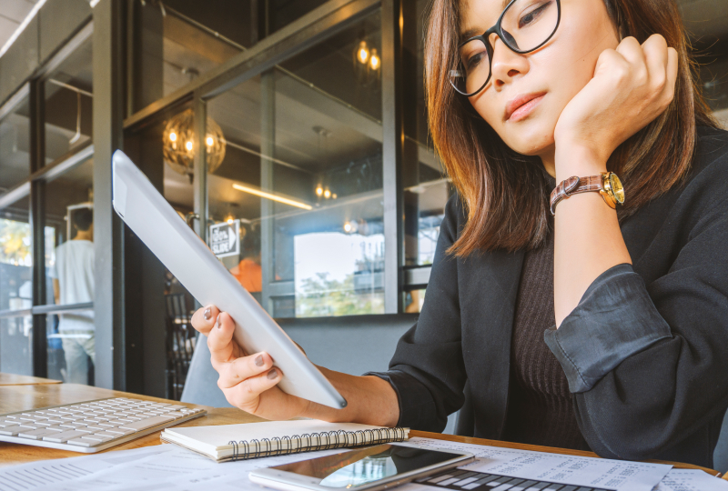 A woman with glasses sitting at a desk reading a notebook