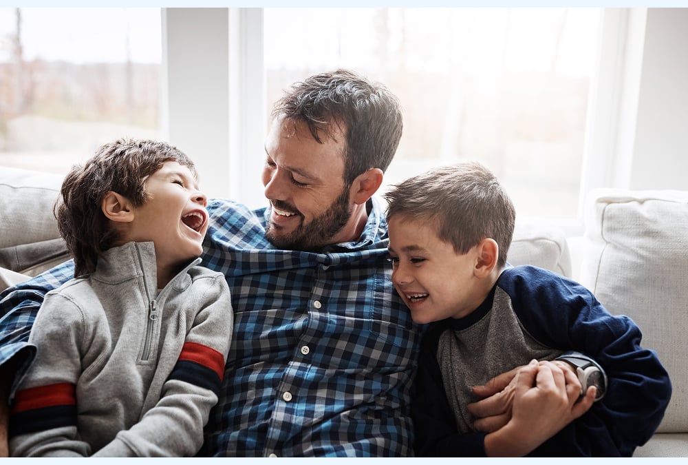 A guy smiling with his arms around his kids